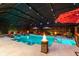 A beautiful screened-in swimming pool with submerged bar stools and fire pit, illuminated at night for relaxation at 4011 99Th W St, Bradenton, FL 34210