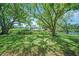 A serene backyard with mature trees, lush green grass, and a tranquil canal view in the distance at 4144 Hampton Dr # C, New Port Richey, FL 34652