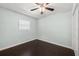 A minimalist bedroom with dark hardwood floors, soft green walls, and a simple window with blinds at 4519 S Grady Ave, Tampa, FL 33611