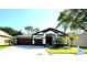 Charming single-story home featuring a two-car garage, manicured lawn, and tropical landscaping at 5554 Riva Ridge Dr, Wesley Chapel, FL 33544