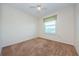 A carpeted bedroom is illuminated by a window fitted with blinds and a green valence at 5712 Biscayne Ct # 205, New Port Richey, FL 34652