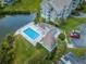 Aerial view of a community pool with seating, surrounded by lush landscaping, and a nearby parking area at 5712 Biscayne Ct # 205, New Port Richey, FL 34652