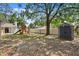 Large backyard with a playset, a storage shed, a spacious lawn, and a large shade tree at 6712 Jennifer Dr, Temple Terrace, FL 33617