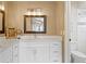 Bright bathroom features white cabinets, modern fixtures, a decorative mirror, and a view of the toilet and shower area at 6712 Jennifer Dr, Temple Terrace, FL 33617