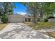Inviting single-story home with a spacious driveway and a lush, green lawn partially shaded by mature trees at 6712 Jennifer Dr, Temple Terrace, FL 33617