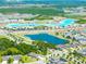 An aerial view of the neighborhood and community lagoon, dotted with palm trees and amenities at 7486 Tuscan Bay Cir, Wesley Chapel, FL 33545
