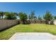 Spacious backyard featuring green grass, trees, with a stone paver patio and sturdy fence surround at 7486 Tuscan Bay Cir, Wesley Chapel, FL 33545