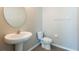 Bright bathroom featuring a pedestal sink, toilet, and neutral color palette at 7486 Tuscan Bay Cir, Wesley Chapel, FL 33545