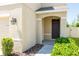 Covered front entrance with a dark-stained front door, stone detail, and manicured shrubbery at 7486 Tuscan Bay Cir, Wesley Chapel, FL 33545