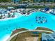 Aerial view of a large lagoon with a beach, a waterpark, and people enjoying water activities at 7486 Tuscan Bay Cir, Wesley Chapel, FL 33545