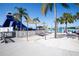 View of a waterslide and sandy area shaded by palm trees and canvas umbrellas at a community lagoon at 7486 Tuscan Bay Cir, Wesley Chapel, FL 33545