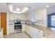 Bright kitchen featuring white cabinets, stainless steel appliances, and ample counter space at 9205 Ledgestone Ln, Port Richey, FL 34668