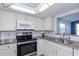Modern kitchen featuring stainless steel appliances, white cabinetry, and neutral countertops at 9205 Ledgestone Ln, Port Richey, FL 34668