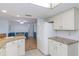 Bright kitchen with white cabinetry, stone countertops, and view into the dining area at 9205 Ledgestone Ln, Port Richey, FL 34668