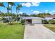 Charming single-story home with a well-maintained lawn, mature palm trees, and a spacious driveway leading to an attached garage at 10828 99Th Pl, Seminole, FL 33772