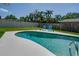 Kidney shaped backyard pool featuring a pristine pool deck, secure fencing, and lush landscaping at 1104 Northridge Dr, Palm Harbor, FL 34683