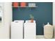 Well-organized laundry room featuring a washer, dryer, storage baskets, and stylish wall color at 11817 Sparkling Topaz Cv, Parrish, FL 34219