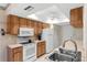 Well-maintained kitchen with white appliances, wood cabinets, and a built-in pantry for ample storage space at 1218 Gillespie N Dr, Palm Harbor, FL 34684