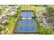 A high angle aerial shot showcases the community tennis courts, the parking area and beautiful landscaping at 1218 Gillespie N Dr, Palm Harbor, FL 34684