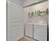 Functional laundry room with a white washer and dryer set and shelving for storing detergents and supplies at 138 Mangrove Shade Cir, Apollo Beach, FL 33572