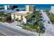 Aerial view showcases complex with pool, palm trees, adjacent street and beach across the street at 1412 Gulf Blvd # 103A, Indian Rocks Beach, FL 33785