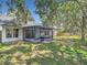 Backyard with screened-in patio, mature trees, and lush green lawn at 1530 High Knoll Dr, Brandon, FL 33511
