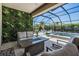 Serene screened-in pool area featuring a comfortable seating area, a stylish fire pit, and a beautiful living wall at 16677 Vibrato Ln, Land O Lakes, FL 34638