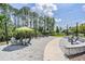 An outdoor seating area features comfortable chairs, umbrellas, brick pavers, and a walkway amidst manicured landscaping at 16677 Vibrato Ln, Land O Lakes, FL 34638