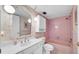 Charming bathroom with a vintage vanity, globe lighting, and a bathtub with pink tile at 17400 Gulf Blvd # I4, North Redington Beach, FL 33708