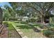 Expansive backyard featuring a large tree, lush greenery, stepping stones, and a swing at 1927 Curry Rd, Lutz, FL 33549