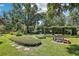 Spacious backyard with mature trees, lush lawn, and landscaped seating areas at 1927 Curry Rd, Lutz, FL 33549