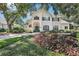Charming two-story home with a well-manicured lawn and garden featuring trees, shrubs, and a green front door at 1927 Curry Rd, Lutz, FL 33549