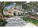 Elegant home with a long driveway, lush landscaping, mature trees, and arched entryway with a green front door at 1927 Curry Rd, Lutz, FL 33549