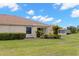 Backyard view of the home and surrounding landscaping featuring vibrant green grass, bushes, and palm trees at 2309 New Orchard Ct, Sun City Center, FL 33573