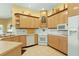 Well-equipped kitchen featuring tile flooring, light wood cabinets, white appliances, and ample counter space at 2309 New Orchard Ct, Sun City Center, FL 33573