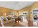 Comfortable living room with hardwood floors, neutral tones, ceiling fan, and access to outdoor screened in patio at 2309 New Orchard Ct, Sun City Center, FL 33573
