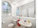 Charming half bathroom features a pedestal sink, toilet, and a frosted arched window for natural light at 2513 Regal River Rd, Valrico, FL 33596