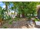 Lush backyard featuring tropical plants, white fencing, mature trees, and a stone pathway at 2525 Madrid S Way, St Petersburg, FL 33712