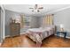 This bedroom features hardwood floors, neutral grey walls, a ceiling fan, and a large window for natural light at 2525 Madrid S Way, St Petersburg, FL 33712