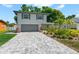 Charming two-story home featuring a gray brick driveway, a two-car garage, and lush landscaping at 2525 Madrid S Way, St Petersburg, FL 33712