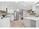 Bright white kitchen featuring stainless steel appliances, tiled backsplash, and access to the upper floor at 2525 Madrid S Way, St Petersburg, FL 33712