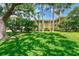 Backside of building with green grass, mature shade trees, and red accents at 2690 Coral Landings Blvd # 122, Palm Harbor, FL 34684