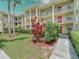 Well-maintained condo building featuring multiple balconies, mature landscaping, and vibrant red door accents at 2690 Coral Landings Blvd # 122, Palm Harbor, FL 34684