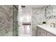 A bright bathroom featuring white marble walls and modern finishes including a shower with a glass door at 400 Island Way # 210, Clearwater Beach, FL 33767