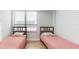 A bedroom featuring twin beds with pink comforters and a large window with blinds, all on wood-look floors at 400 Island Way # 210, Clearwater Beach, FL 33767