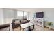 Cozy living room featuring a comfortable sofa, entertainment center, and a sliding glass door to a balcony at 400 Island Way # 210, Clearwater Beach, FL 33767