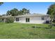 Backyard view of the house, green grass, patio, sliding glass door and shrubbery at 4148 102Nd N Pl, Clearwater, FL 33762