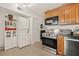 Cozy kitchen with wooden cabinets, stainless steel appliances, and a compact washer/dryer unit at 476 Santa Cruz Ne Pl # C, St Petersburg, FL 33703