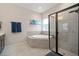 Bright bathroom with a corner tub, tiled floors, a glass-enclosed shower, and double-hung windows at 5609 Silver Sun Dr, Apollo Beach, FL 33572
