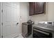 Convenient laundry room with modern appliances, overhead cabinets, and a white door at 5609 Silver Sun Dr, Apollo Beach, FL 33572